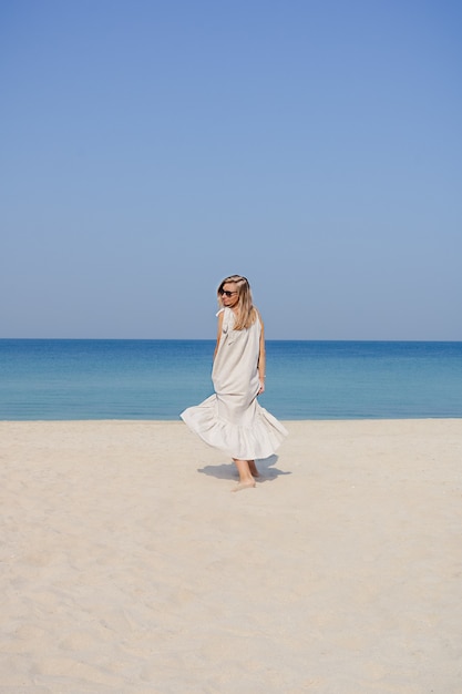 Blondynka W Lnianej Sukience Maxi Z Rozwianymi Włosami, Skacząca I Tańcząca Na Piaszczystej Plaży