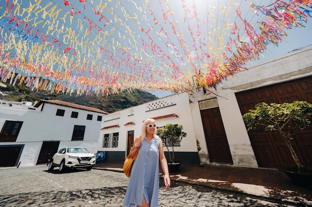 Blondynka w sukience z plecakiem spaceruje ulicą Starego Miasta Garachico na TeneryfieHiszpania Wyspy Kanaryjskie