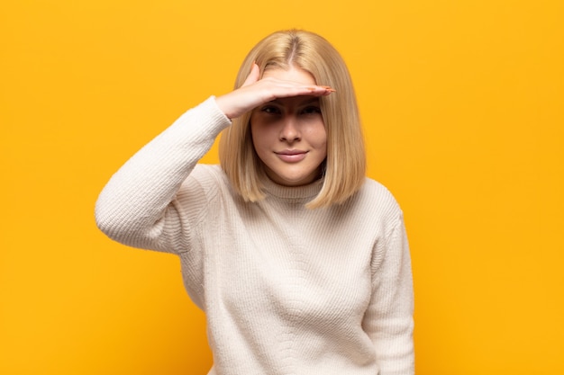 blondynka wyglądająca na oszołomioną i zdumioną, z ręką na czole spoglądającą w dal, obserwującą lub szukającą