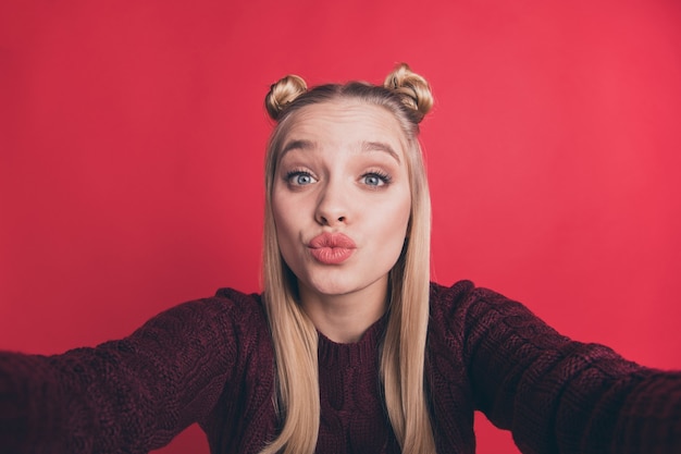 blondynka z top-knots pozuje i robi selfie na czerwonej ścianie