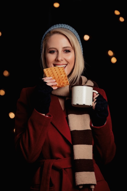 Zdjęcie blondynki dziewczyna z filiżanką kawy i gofrem