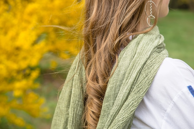 Blondynki dziewczyna z zielonym bagna eleganckim szalikiem wśród jaskrawych żółtych kwiatów