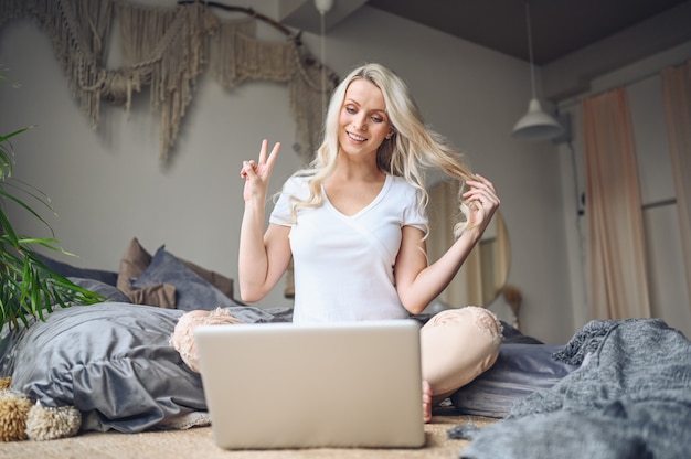 Blondynki kobieta pracuje na laptopie w sypialni