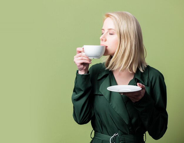 Blondynki kobieta w pelerynie z filiżanką kawy