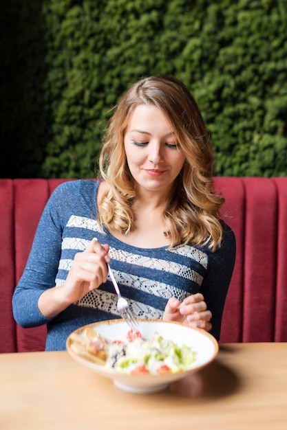 Blondynki ładna kobiety łasowania sałatka. Klient degustujący pyszny posiłek w restauracji.