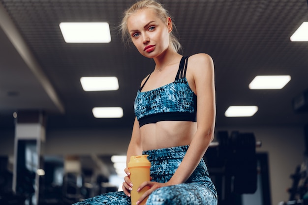 Blondynki szczupła dysponowana kobieta w sport odzieży w ciemnym gym