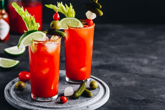 Bloody Mary Cocktail w okularach z dodatkami Pomidorowy Bloody Mary lodowaty napój ze świeżymi piklami z selera i limonką na ciemnym tle