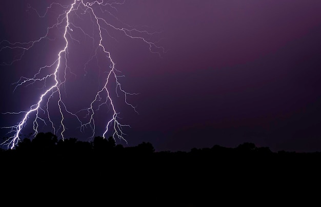 Błyskawica nad sylwetką pola na tle nocnego nieba