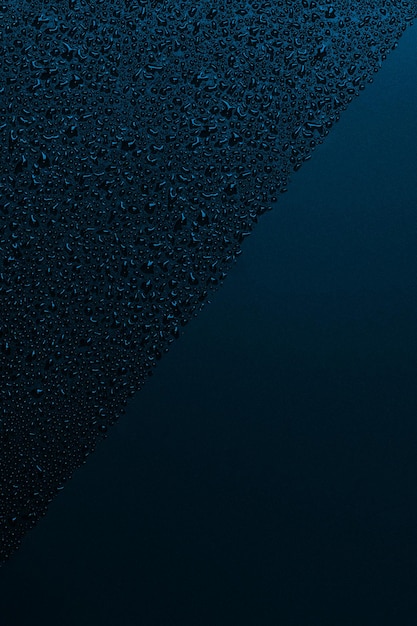 Błyszcząca woda spada na czarną powierzchnię niebieskie tło krople wody na czarnej powierzchni krople wody na czarnej szklanej powierzchni Tekstura Widok z góry