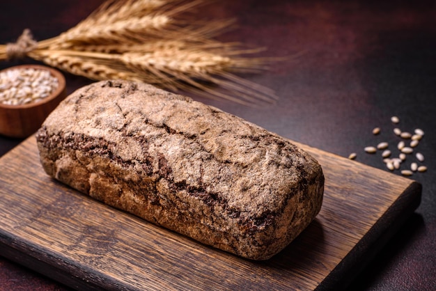 Bochenek brązowego chleba z ziarnami zbóż na drewnianej desce do krojenia