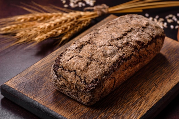 Bochenek brązowego chleba z ziarnami zbóż na drewnianej desce do krojenia