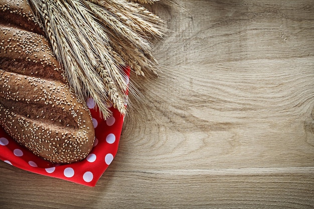 Bochenek chleba kłosy pszenicy czerwony obrus polkadot na desce
