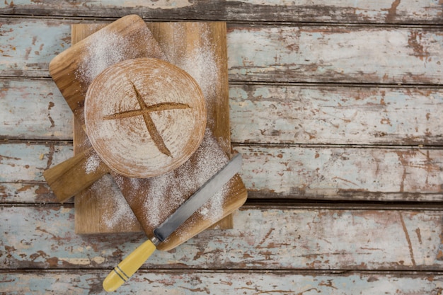 Zdjęcie bochenek chleba z mąką pszenną i nożem