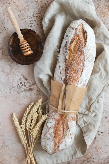 Bochenek rzemieślniczego chleba na zakwasie z lawendą i miodem na lnianej serwetce z pszenicznymi kłosami