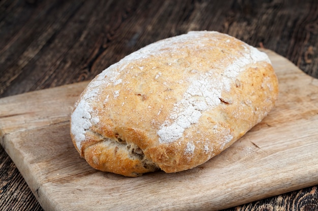 Zdjęcie bochenek świeżego chleba pszennego na stole podczas gotowania, miękki świeży chleb z pestkami dyni i nasionami lnu