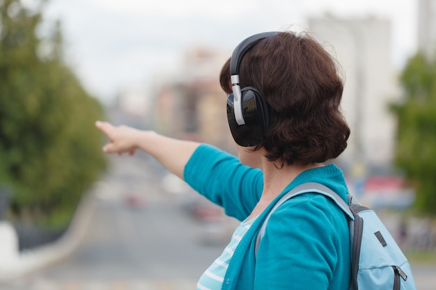 Zdjęcie bocznego widoku młodej kobiety odprowadzenie w miasta plecy świetle słucha muzycznych hełmofony