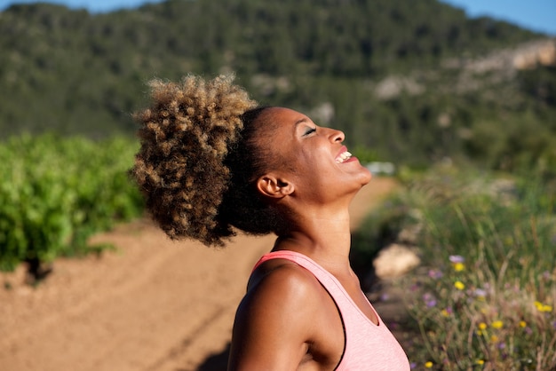 Boczny portret zdrowa młoda afrykańska kobieta śmia się outdoors w ranku