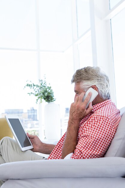 Boczny widok opowiada na telefonie mężczyzna podczas gdy trzymający cyfrową pastylkę