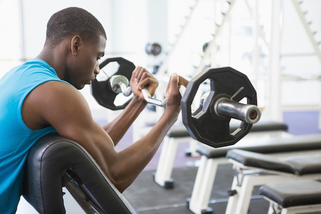 Boczny widok zdecydowanego młodego mięśniowego mężczyzna podnośny barbell w gym