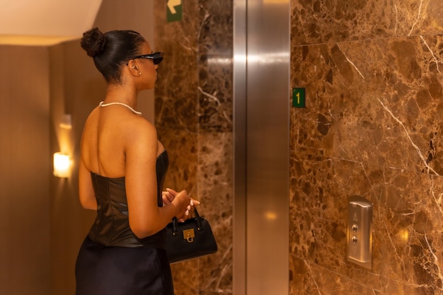 Bogata czarna etniczna kobieta biorąca luksusową koncepcję windy hotelowej