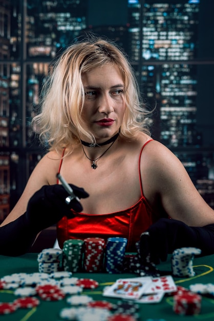 Bogata kobieta nosi wieczorową czerwoną sukienkę, grając w pokera, trzymając cygaro