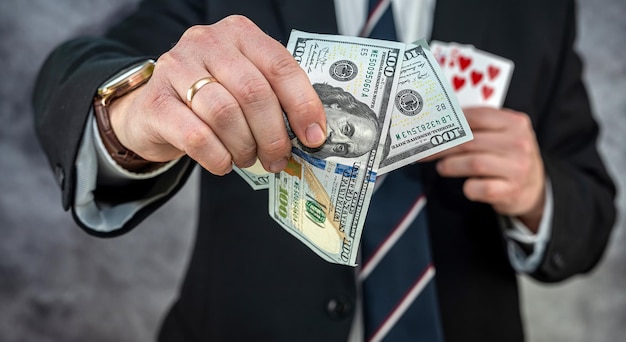 Bogaty biznesmen trzymający dolara i karty do gry w pokera, powodzenia