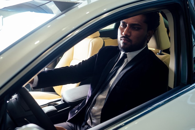 Bogaty indyjski biznesmen w formalnym stroju prowadzi samochód