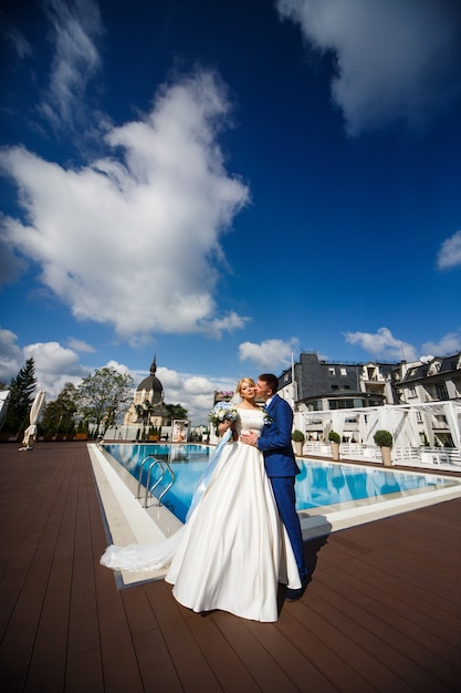 Zdjęcie bogaty ślub para pozuje przed waterpool na zewnątrz