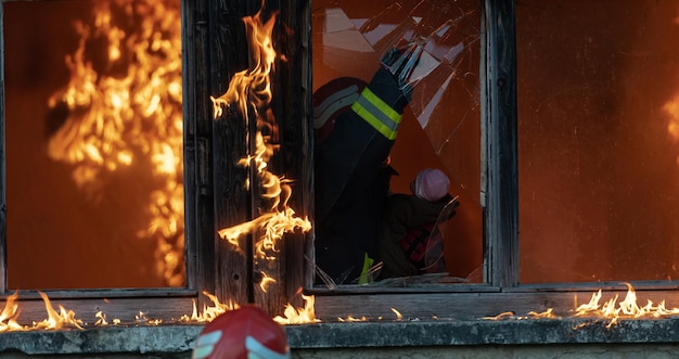 Zdjęcie bohater strażaka niosącego córeczkę z płonącego budynku z incydentu pożarowego. ratuj ludzi z niebezpiecznego miejsca. praca zespołowa zdjęcie wysokiej jakości