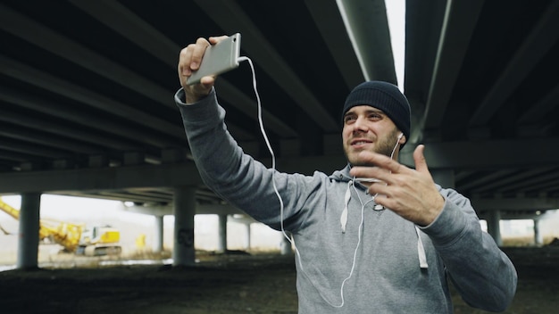 Bokser prowadzi czat wideo na smartfonie z przyjaciółmi po treningu w lokalizacji miejskiej