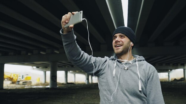 Bokser prowadzi czat wideo na smartfonie z przyjaciółmi po treningu w lokalizacji miejskiej