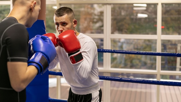 Zdjęcie bokser w kasku i rękawiczkach trenujący z człowiekiem