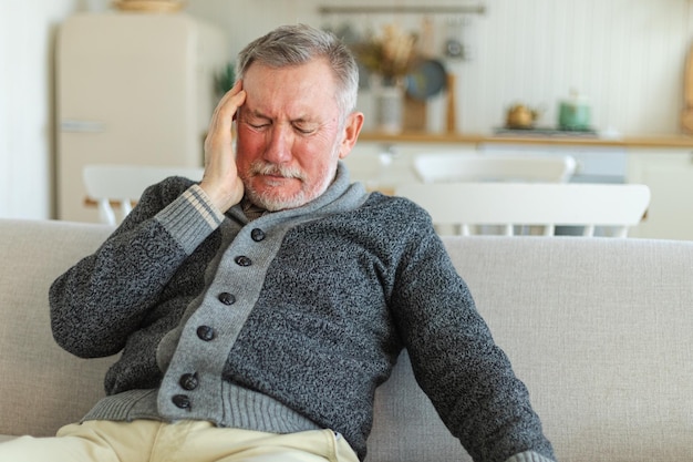 Ból głowy ból nieszczęśliwy starszy mężczyzna w średnim wieku cierpiący na ból głowy chory pocierający skronie w domu ma