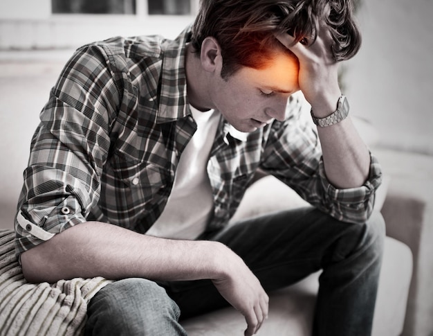 Zdjęcie ból głowy mężczyzny i stres na domowej kanapie podczas depresji, wypalenia i cierpienia ze zdrowiem psychicznym lub bólem mężczyzna z czerwoną poświatą z powodu zmęczenia, niepokoju i mgły mózgowej lub pomyłki, gdy jest zmęczony na kanapie