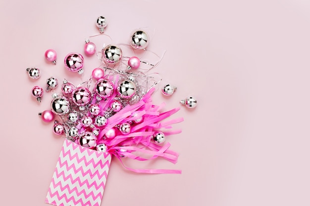 Bombki płynące z torby prezent na różowym tle Płaski świeckich, widok z góry modny koncept wakacyjny.