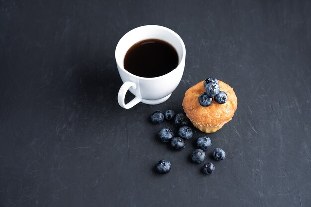 Borówkowy przeciwutleniacz organiczny superfood i słodka muffinka z filiżanką kawy Koncepcja zdrowego odżywiania i odżywiania Widok z góry na ciemnym czarnym tle