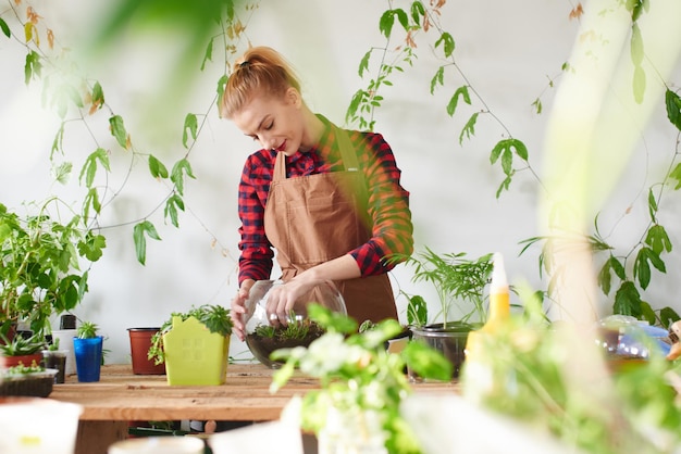 Botanika. Kobieta kwiaciarnia uprawia rośliny domowe i kwiaty. Zrób mini terrarium