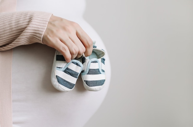 Botki W Rękach Przyszłej Mamy Z Brzuchem W Ciąży