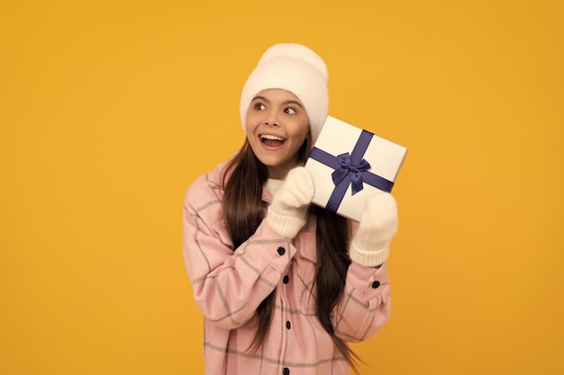 Boxing day szczęśliwego nowego roku wesołych świąt zdumiony dzieciak w zimowej czapce z pudełkiem