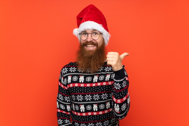 Boże Narodzenie człowiek z długą brodą na pojedyncze czerwone ściany z kciuki do góry, ponieważ stało się coś dobrego