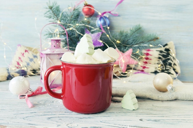 Boże Narodzenie filiżanka kawy z piankami marshmallow lampion z płonącą świecą gałązki świerkowe