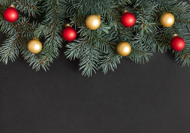 Boże Narodzenie granica z gałęziami jodły, czerwonymi i złotymi kulkami na czarnym tle.