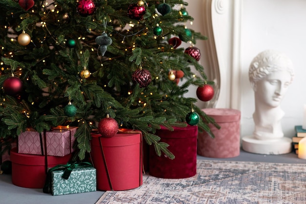 Boże Narodzenie i nowy rok tło - pudełka na prezenty i lekkie girlandy, bokeh, w pobliżu ozdobionej choinki. Miękka selektywna ostrość.