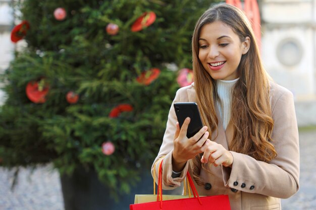 Boże Narodzenie Kobieta Kupowanie Online Na Smartfonie Na Ulicy Z Choinką W Tle.