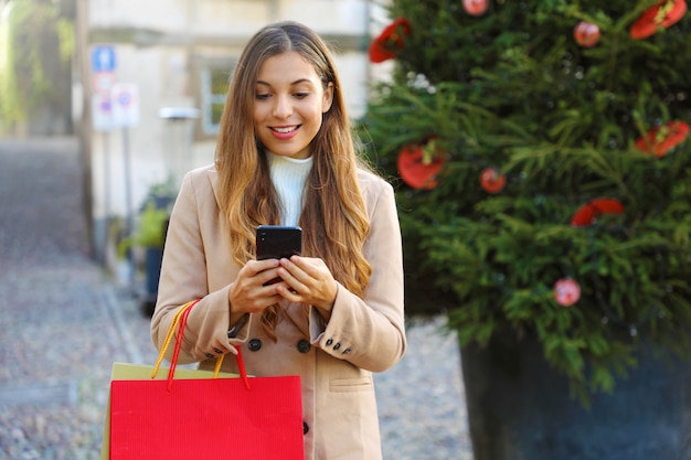 Boże Narodzenie kobieta kupuje online na smartfonie na ulicy.