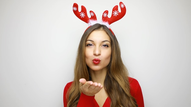 Boże Narodzenie kobieta z czerwonymi ustami wysyła pocałunek z rogami renifera na głowie