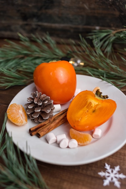 Boże Narodzenie martwa natura ze świeżym persimmon z szyszek sosny, cynamonu, prawoślazu i mandarynki