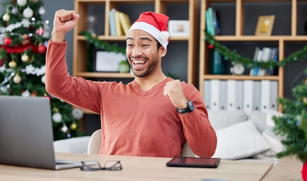 Boże Narodzenie na laptopie i praca zdalna ze zwycięzcą w jego domowym biurze na obchody sukcesu Komputerowy sukces i motywacja ze szczęśliwym przedsiębiorcą dopingującym premię lub ofertę sprzedaży