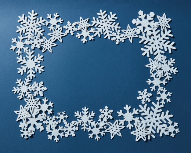 Zdjęcie boże narodzenie ozdobna rama płatków śniegu. na niebieskim tle.