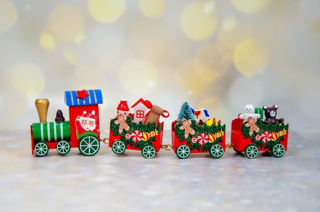 Boże Narodzenie pociąg na tle złotego światła bokeh. Santa Claus czerwony drewniany zabawka pociąg z wagonami. Selektywne skupienie. Kartkę z życzeniami Wesołych Świąt i szczęśliwego nowego roku. miejsce na tekst.